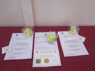 three tennis balls are in clear boxes on a red table