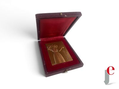 une médaille d'or dans un coffret en bois posé sur une surface blanche