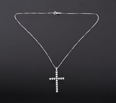 un pendentif en forme de croix en diamant, suspendu à une chaîne, sur fond noir