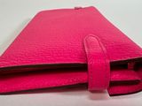 a pink leather wallet with a zipper on top of it