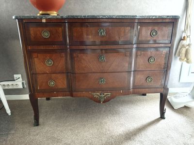 une commode avec un plateau en marbre sur lequel est posé un vase