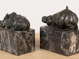two statues of rhinos on marble blocks on a table