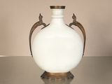 a white vase sitting on a table with two birds on it