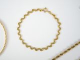 two gold chains and a gold bracelet on a white surface