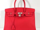 un sac à main en cuir rouge muni d'un cadenas sur la poignée
