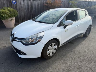 une voiture blanche garée sur un parking près d'une clôture en bois