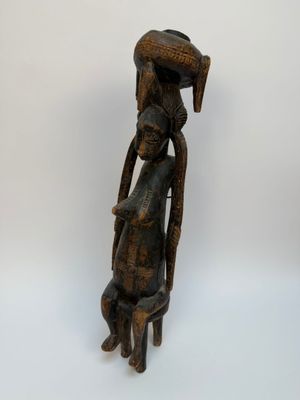 une vieille statue en bois représentant une femme avec un panier sur la tête
