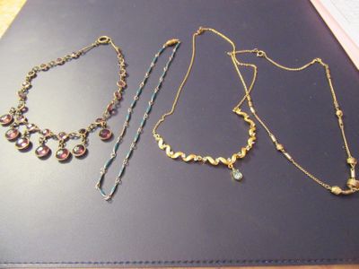 three necklaces and a bracelet sitting on a table
