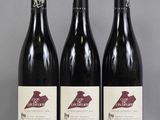 three bottles of red wine are lined up on a table