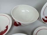 a white table topped with bowls and plates with red paint on them