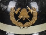 a black and gold helmet with a bell and two crossed axes