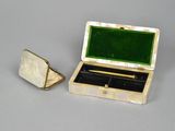 a small box with a pen in it sitting next to a pair of cufflinks