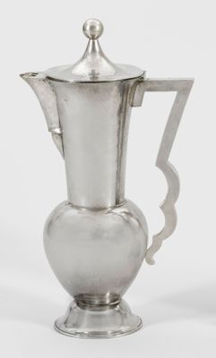 cafetière plaquée argent avec une anse incurvée sur fond blanc