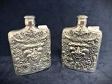 two silver flasks with a face on them on a black background