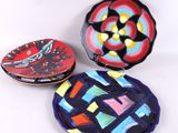 trois assiettes colorées ornées de motifs, posées sur une surface blanche