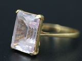 a close up of a ring with a pink stone on a black surface