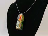 a necklace that has a bottle on it on a mannequin