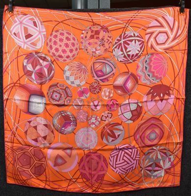 an orange scarf with a bunch of different designs hanging on a wall