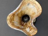a brown and white vase with a black ball in it