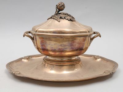 une assiette en argent sur laquelle est posé un oiseau, posée sur une soucoupe