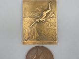 une petite médaille en bronze sur laquelle est représenté un oiseau
