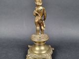 brass figurine of a boy holding a bird on a pedestal