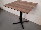 a wooden table with a black metal base in a room