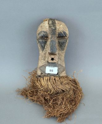 une image représentant un masque en bois sur lequel est accrochée une étiquette