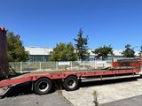 une remorque à plateau rouge garée sur un parking