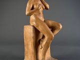 a statue of a woman sitting on top of a wooden block