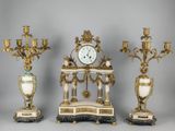 trois horloges anciennes et un support d'horloge alignés sur un fond gris