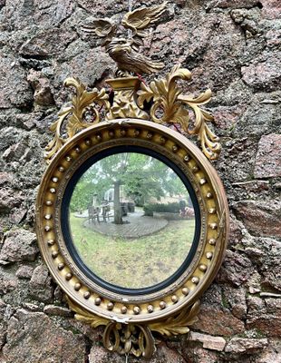un miroir accroché à un mur de pierre, sur lequel est représenté un oiseau