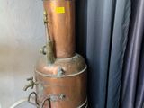 a large copper pot sitting on top of a metal stand