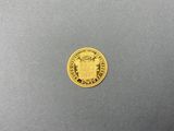 a close up of a gold coin on a gray surface