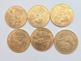 six gold sovereigns of different sizes and shapes on a white surface