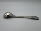 une cuillère en argent posée sur une table, sur fond blanc