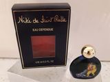 un flacon de parfum dans une boîte transparente posée sur un comptoir, avec une boîte de parfum en arrière-plan