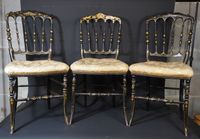 Suite de trois chaises en bois peint noir à dossier ajouré.