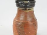 a brown vase with a black top sitting on a white surface