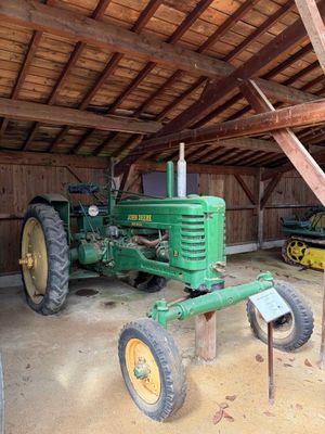 un tracteur vert dans une grange au toit en bois