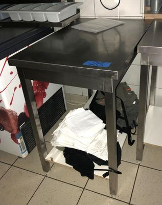 une table en acier inoxydable sur laquelle est posé un ordinateur portable, dans une cuisine