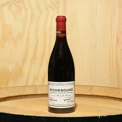 a bottle of wine sitting on top of a barrel