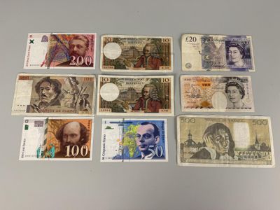 Plusieurs billets de banque différents sont disposés en rangée sur une table
