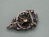 a silver brooch with a flower and a sword