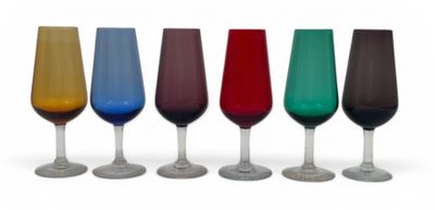 six verres à vin de couleurs différentes alignés sur une surface blanche