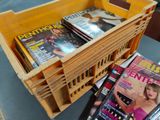 a basket of magazines on a table next to a stack of magazines