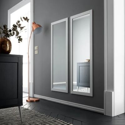deux miroirs accrochés au mur, à côté d'une armoire noire