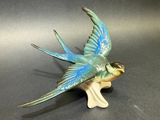 une figurine d'oiseau bleue et verte posée sur une table