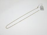 une chaîne en or à laquelle est accrochée une médaille, posée sur une surface blanche