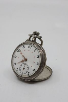 a silver pocket watch sitting on top of a white surface
